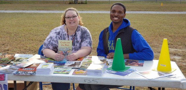 Two people handing out books.